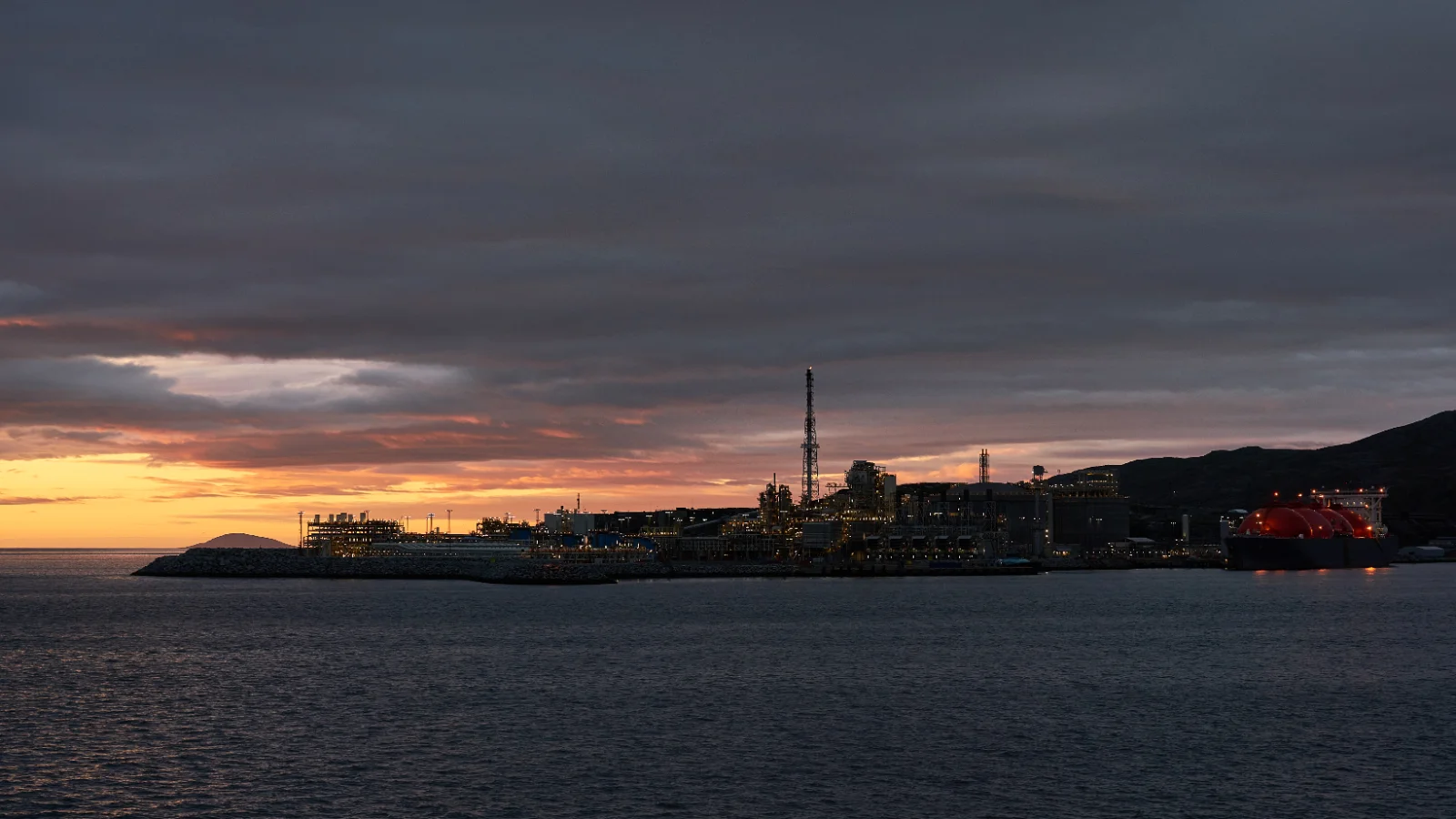 An onshore LNG liquefaction and export terminal with storage tanks and a loading jetty